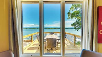 A room with a large window overlooking a deck with a table and chairs.