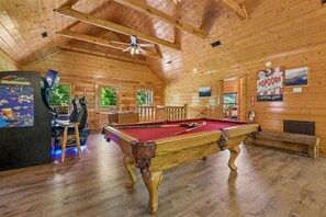 A wooden interior with a pool table, a gaming table, and a popcorn sign. - Premier Riverfront Retreat w/ Hot Tub & Games (Pigeon Forge)