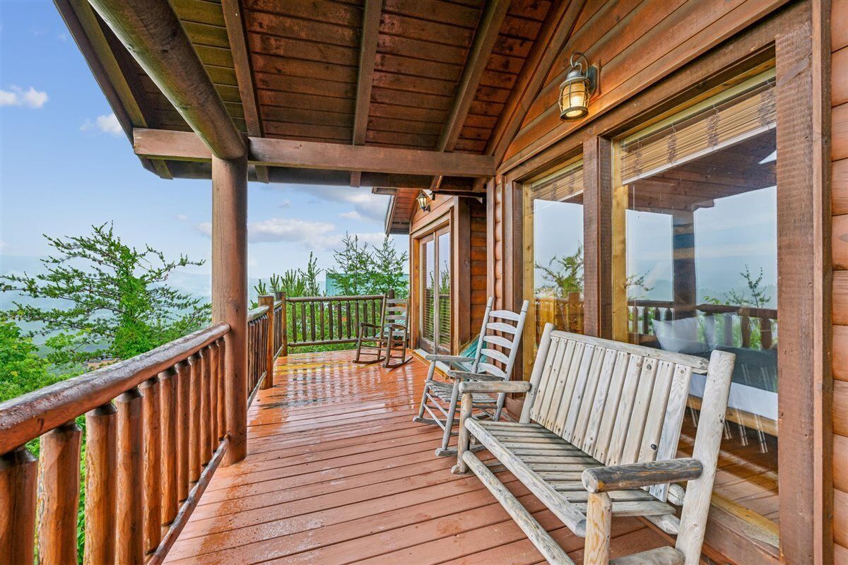 Eine Holzterrasse mit Bank und Stühlen mit Blick auf eine natürliche Landschaft.