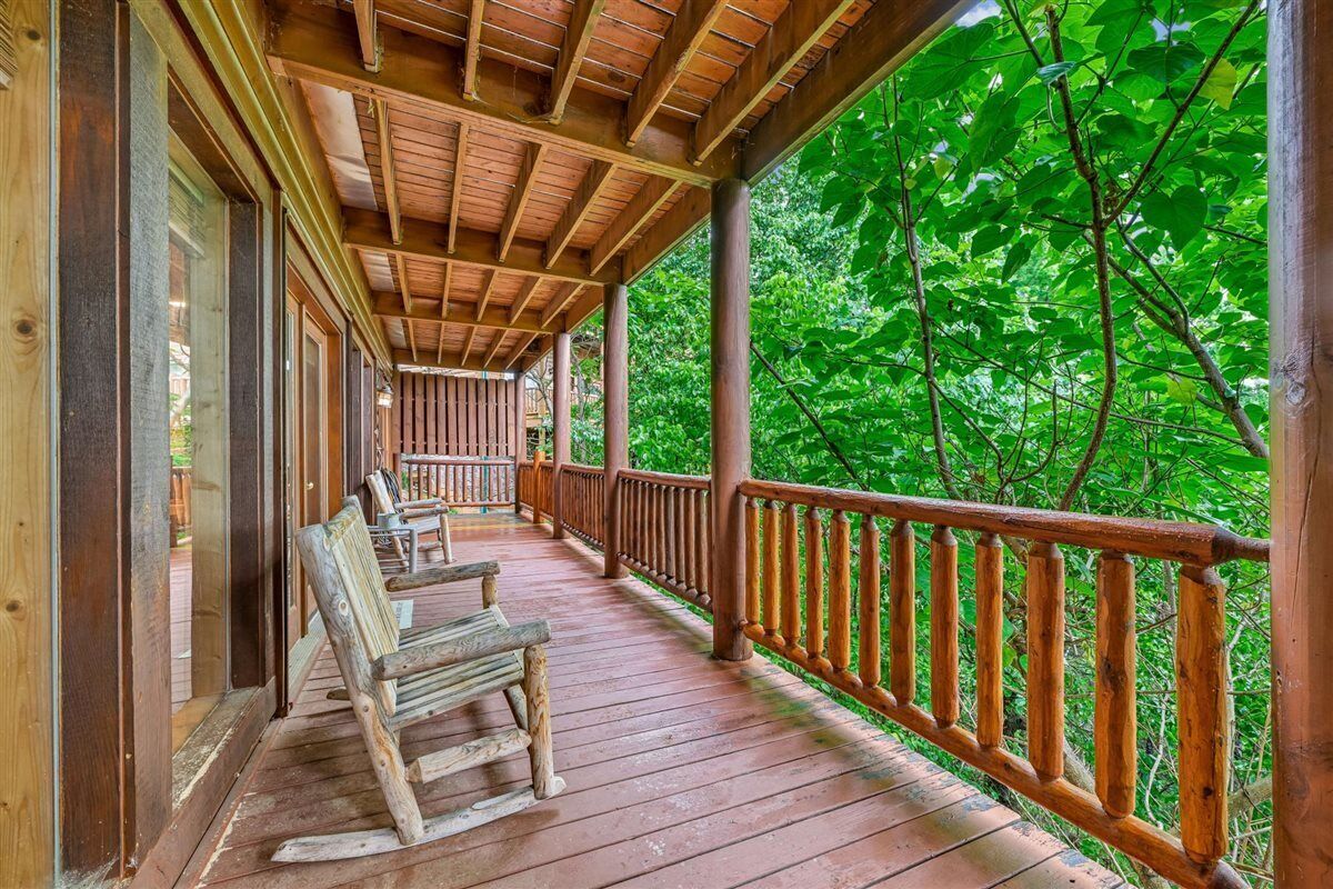 Une terrasse en bois, dotée de bancs, entourée d’arbres.