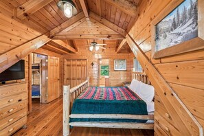 A wooden cabin interior with a bed, a television, and a framed picture on the wall. - Majestic Lodge w/ Views, Hot Tub & Games (Sevierville)