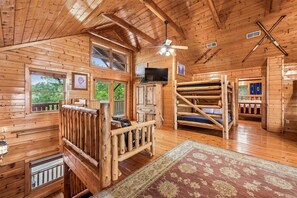 A log cabin interior with a bed, a television, and a fireplace. - Majestic Lodge w/ Views, Hot Tub & Games (Sevierville)
