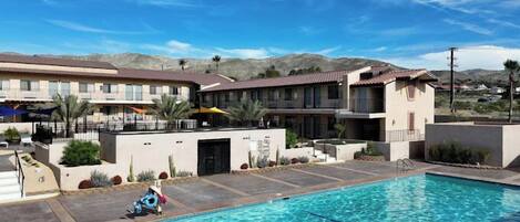 Un hotel con piscina, zona de estar al aire libre y vistas a montañas.