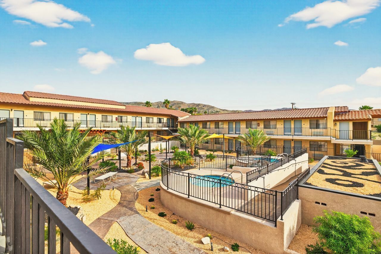 A hotel with multiple balconies, a swimming pool, and a landscaped courtyard.
