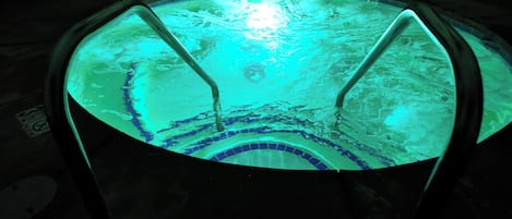 A circular hot tub with a tiled interior and two metal ladders.