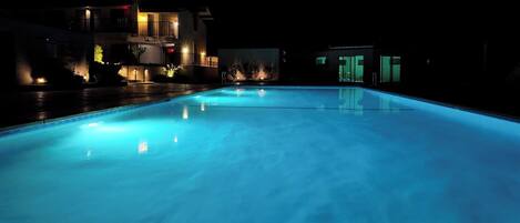 Een buitenzwembad, parasols voor strand/zwembad