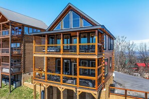 A multi-story log cabin with balconies and large windows. - Modern Luxe Cabin w/ Views, Games & Hot Tub (Sevierville)