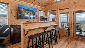 En inredning med träpaneler, en bardisk, sittplatser och en stor TV-skärm.