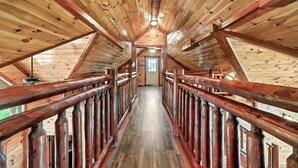 Un interior de madera con una escalera central de madera que lleva a una puerta al final.