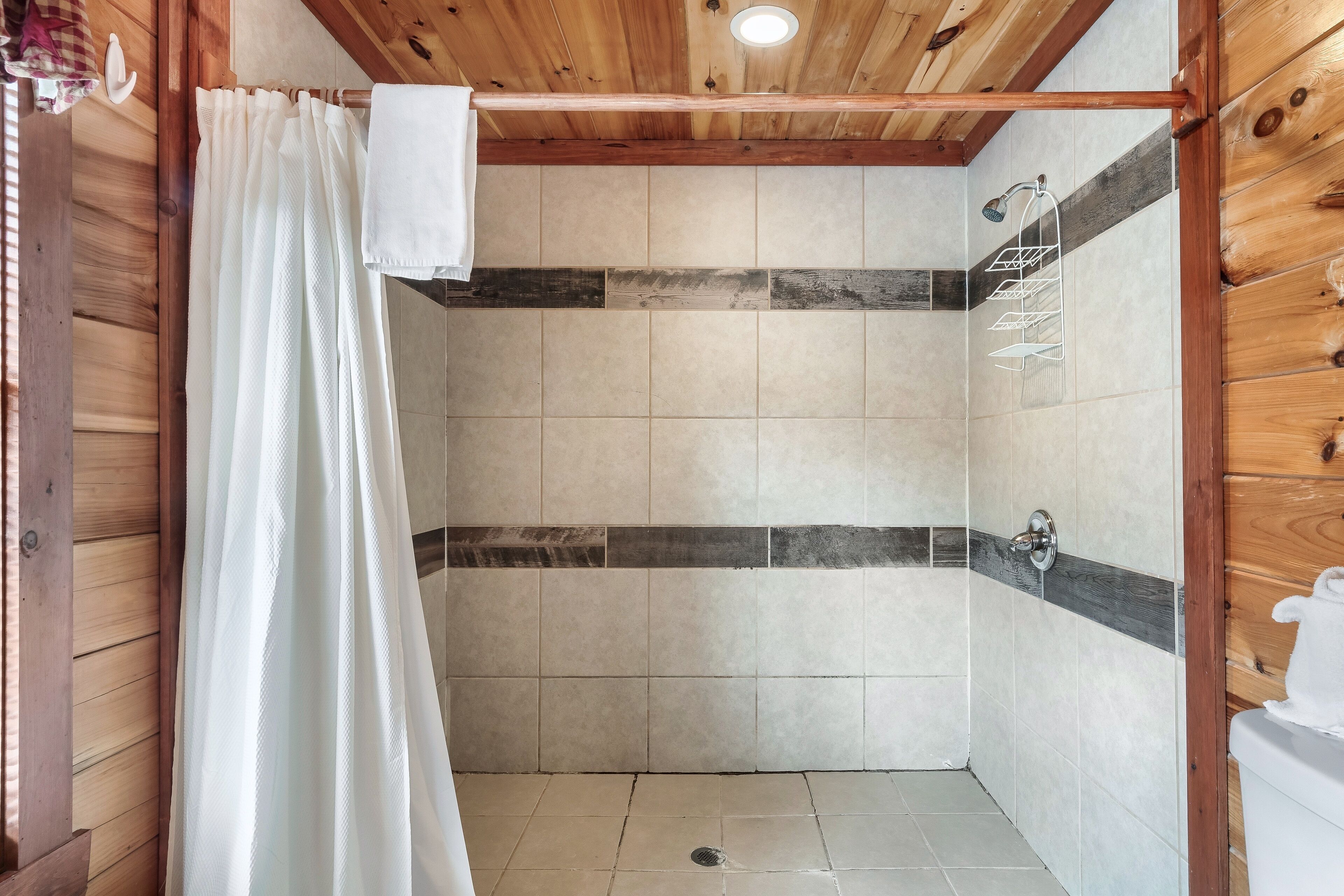 A shower area with wooden beams, tiled walls, and a showerhead.