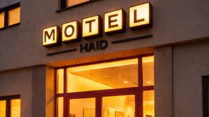 A motel entrance with illuminated signage, a glass door, and a visible interior through the door. - 1 room 59€ (double bed 2person) (Ansfelden)