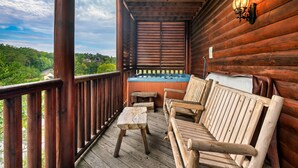 A wooden deck with a hot tub, wooden furniture, and a view of greenery. - Grand Mountain Retreat w/ Games & Hot Tub (Pigeon Forge)