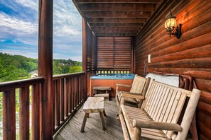Eine Holzterrasse mit Whirlpool, Holzmöbeln und Blick auf Grünflächen.