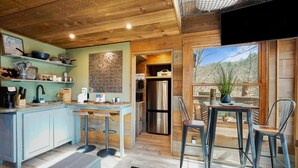A modern kitchen with a wooden ceiling, a brick wall, and a large window with a view of trees. - Rustic Wooded Escape w/ Hot Tub and Views (Sevierville)