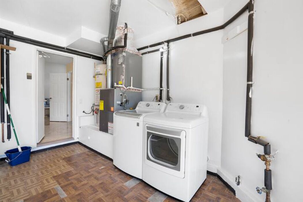 A laundry room with stacked washers and dryers, a mop, and a broom.