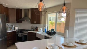 Una cucina moderna con mobili in legno, un frigorifero in acciaio inossidabile, un fornello a gas e luci a sospensione.
