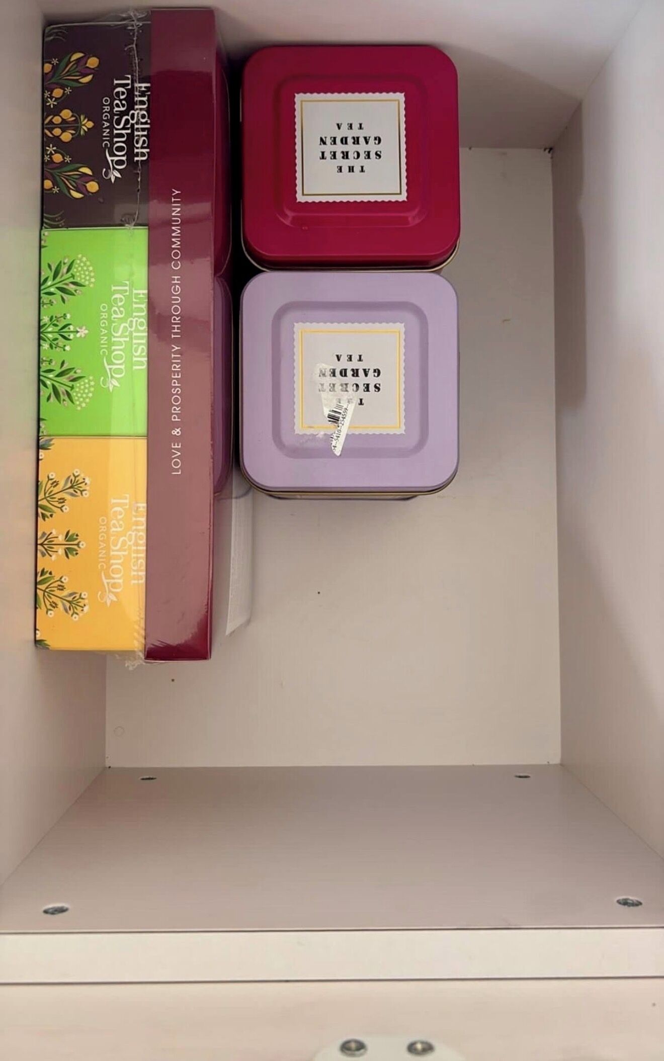 Een opslagruimte met drie containers, gelabeld 'English Tea Shop Organic' en 'Garden Secret Tea'.