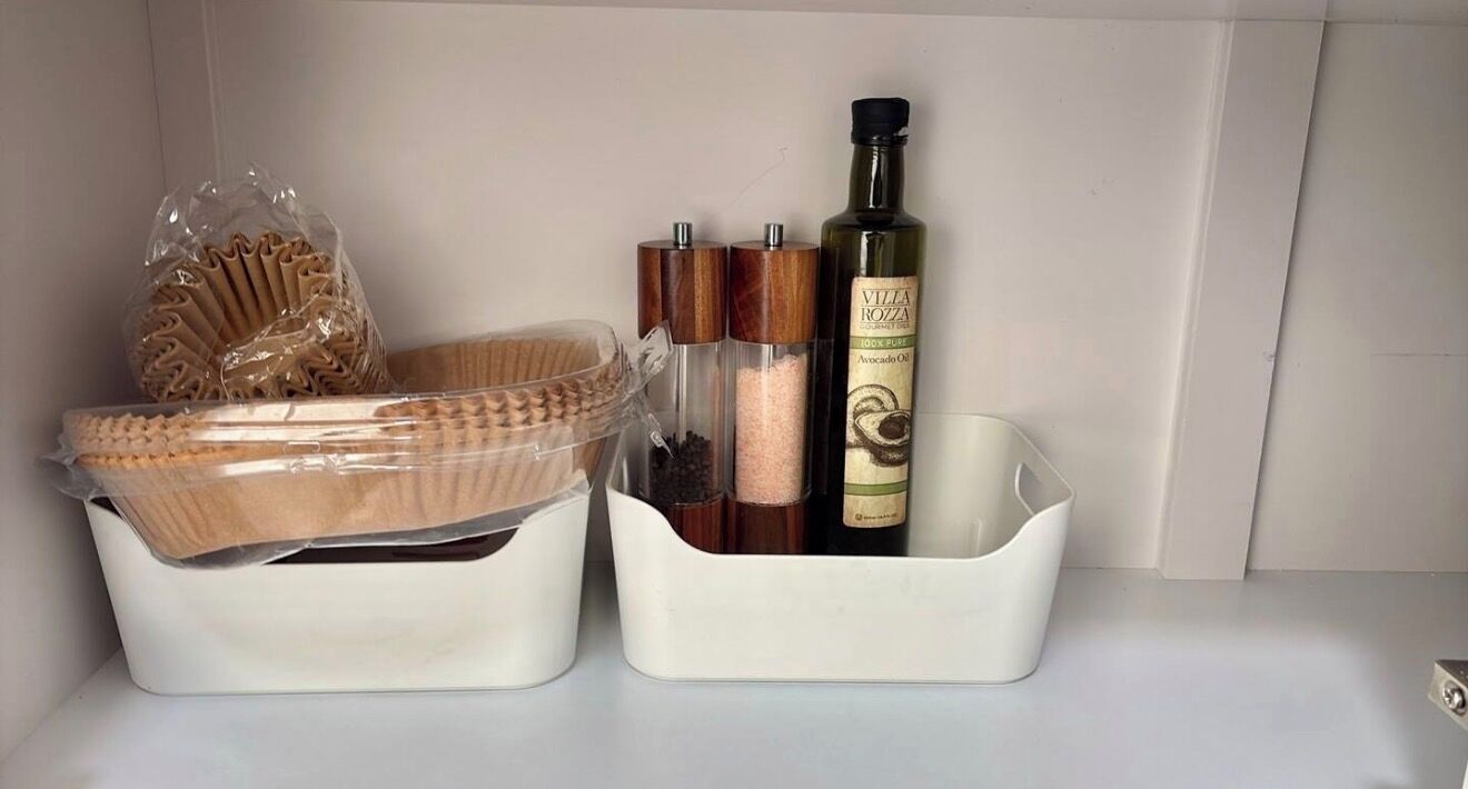 Un piano di lavoro in cucina con contenitori portaoggetti contenenti diversi utensili da cucina.