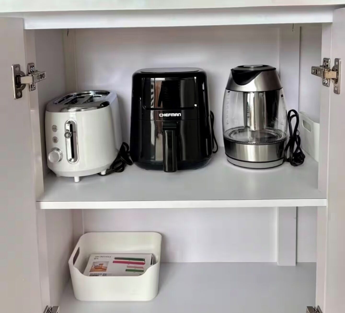 A kitchen with a toaster, a coffee maker, and a kettle on the countertop.