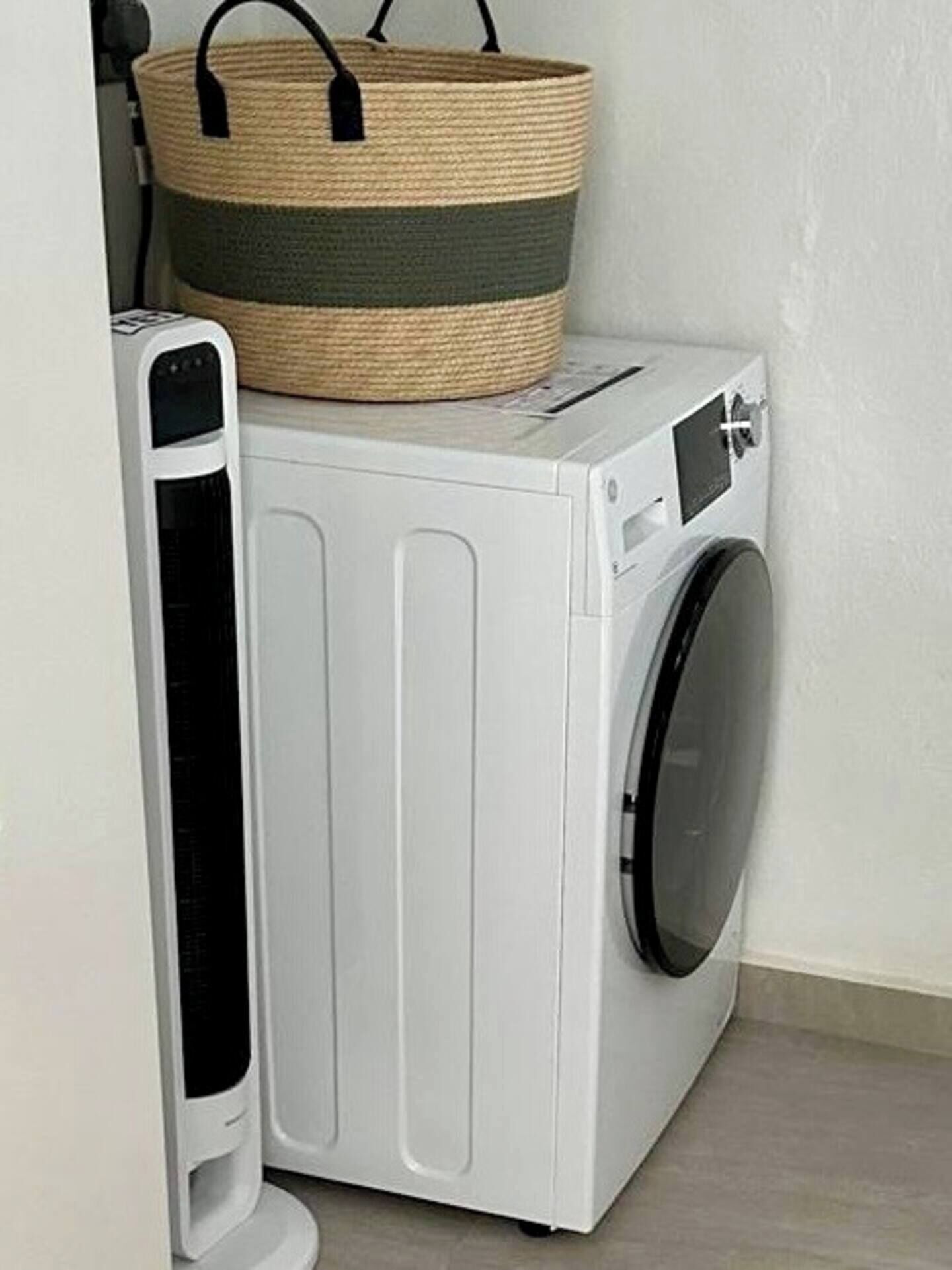 A white front-loading washing machine with a basket on top.