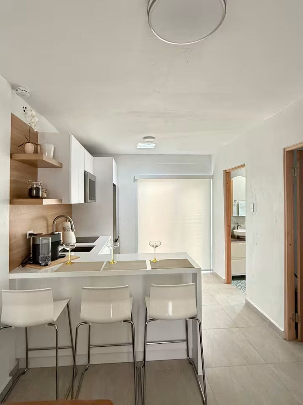 Una cocina moderna con una isla central, taburetes de bar y electrodomésticos integrados.