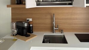 Eine moderne Küche mit eingebautem Geschirrspüler, einer Spüle und einer Kaffeemaschine.