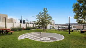 A landscaped area with a circular concrete feature, benches, and a tree. - Modern Apartment with Pool in Querétaro (El Marques)