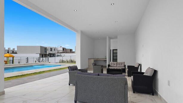 A modern outdoor living area with a pool, seating, and a view of the cityscape. - Modern Apartment with Pool in Querétaro (El Marques)