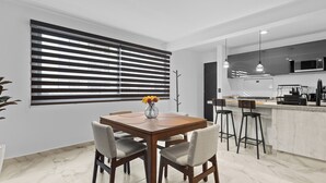 A modern kitchen with a microwave, stove, and bar stools. - Modern Apartment with Pool in Querétaro (El Marques)