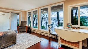 Ein gemütliches Zimmer mit einem großen Fenster, einem Sessel, einem Tisch mit einem Puzzle und einem Teppich.
