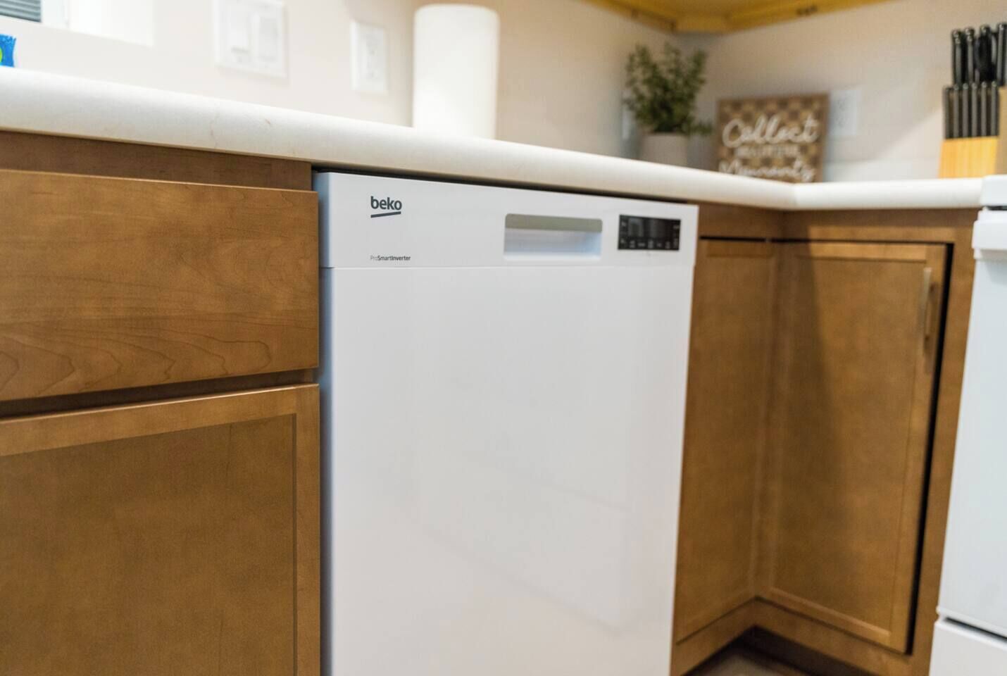 A kitchen with wooden cabinets and a white dishwasher.