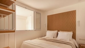 A bedroom with a bed, a wooden headboard, a window, and a built-in shelf. - Carla Rosa 5 Apartement Terrazza - 2 BDR Piscine (Cannes)