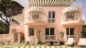 A pink building with balconies, a pool, and outdoor seating. - Carla Rosa 5 Apartement Terrazza - 2 BDR Piscine (Cannes)