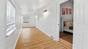 En hall med trägolv, vita väggar och en säng med en sänggavel i rummet.
