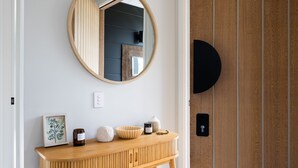 A wooden console table with a mirror above it, a framed picture, and a candle. - The Bird House Manyana (Manyana)
