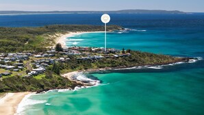 Vista aérea de una zona residencial costera con casas, una playa y un faro.