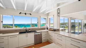 Una cocina moderna con ventanas amplias que ofrecen vistas al océano, lavavajillas y horno empotrado.