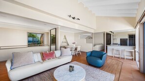 Una sala moderna con un sofá blanco, un sillón azul y una mesa de centro redonda.