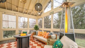 A sunroom with a fire pit, seating area, and large windows. - Wright Stay: Hot Tub, Game Room, Sunroom, Fire-Pit (Dayton)