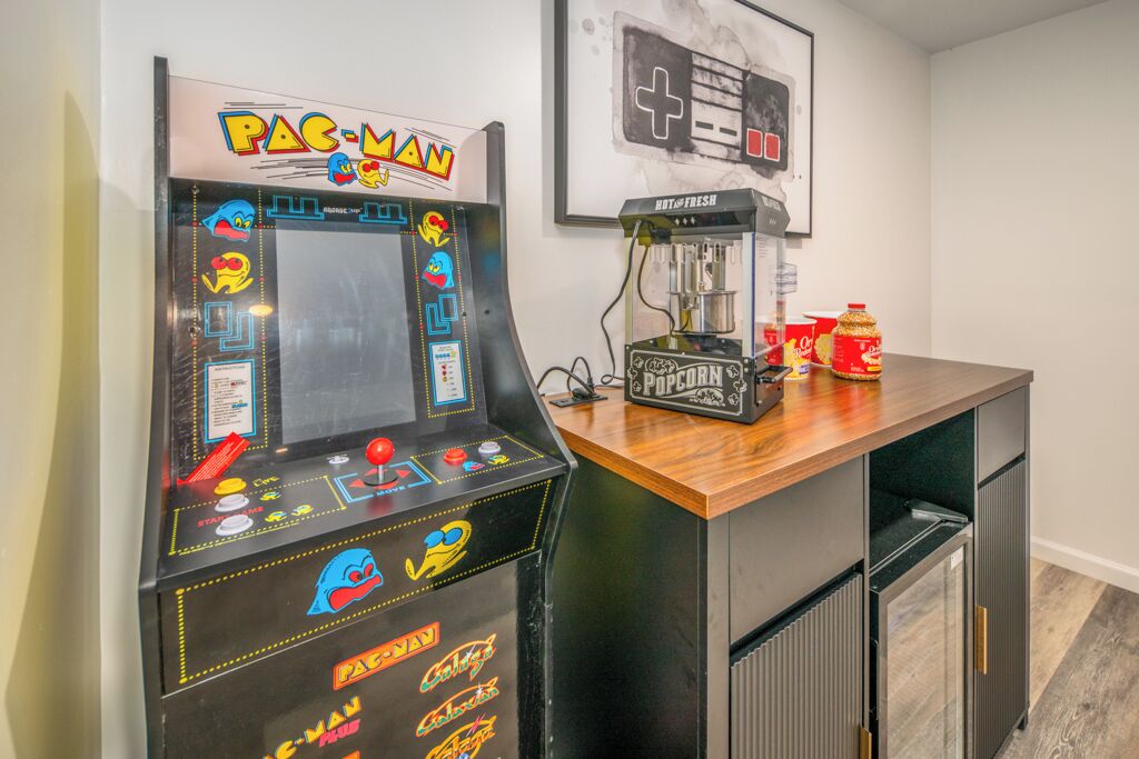 Una macchina arcade Pac-Man, una macchina per pop-corn e una console Nintendo 64 su un bancone di legno.