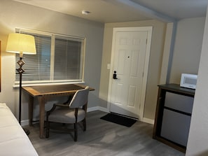 A compact kitchen with a dining table, a chair, a microwave, and a door.