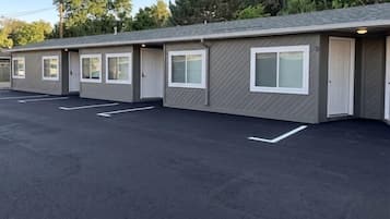 Une rangée de chambres de motel, chacune avec sa propre porte d’entrée, un parking et un bâtiment portant le numéro « 8 ».