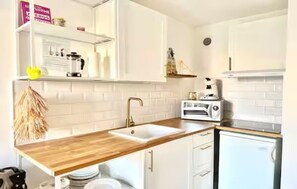 A kitchen with white cabinets, a wooden countertop, a sink, a toaster, and a refrigerator. - Patio Sable sleeps 4,☀️Climatisé☀️Piscine☀️Parking (Palavas-les-Flots)