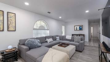 A modern living room with a grey sectional sofa, a coffee table, and a TV on a stand.