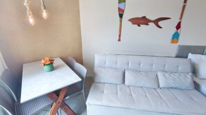 Une pièce avec une table blanche, un canapé gris et un mur décoré avec un motif de poissons.