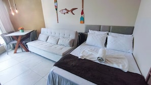 A hotel room with two beds, a small table with a chair, and a wall-mounted fish decoration.