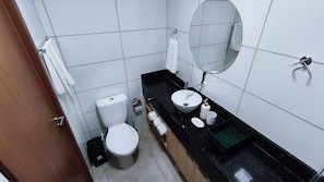 Ein kleines Badezimmer mit Toilette, Waschbecken, Spiegel und Handtuchhalter.