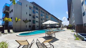 Un edificio moderno con piscina, zona de estar exterior y patio amurallado.