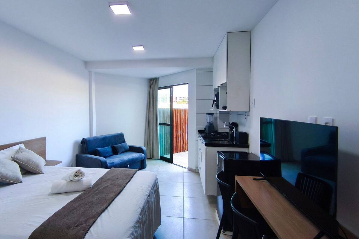 Une chambre d’hôtel équipée d’un lit, d’un bureau, d’une chaise, d’une télévision et d’une kitchenette.