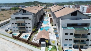 Ein modernes Hotel mit mehreren Swimmingpools, einem Innenhof und Blick auf die umliegenden Gebäude.
